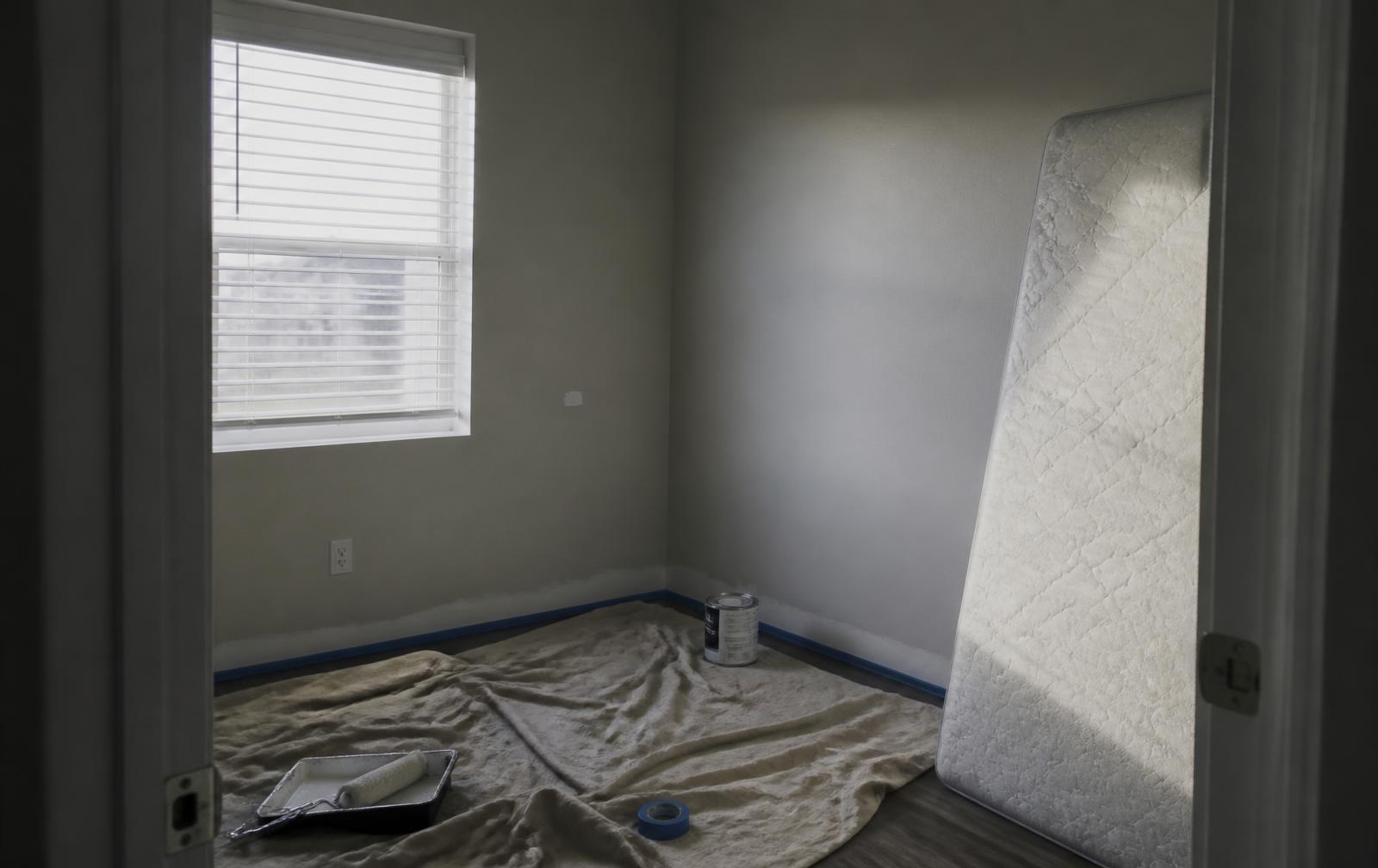 Empty student apartment bedroom mid make-ready with drop cloth and fresh paint