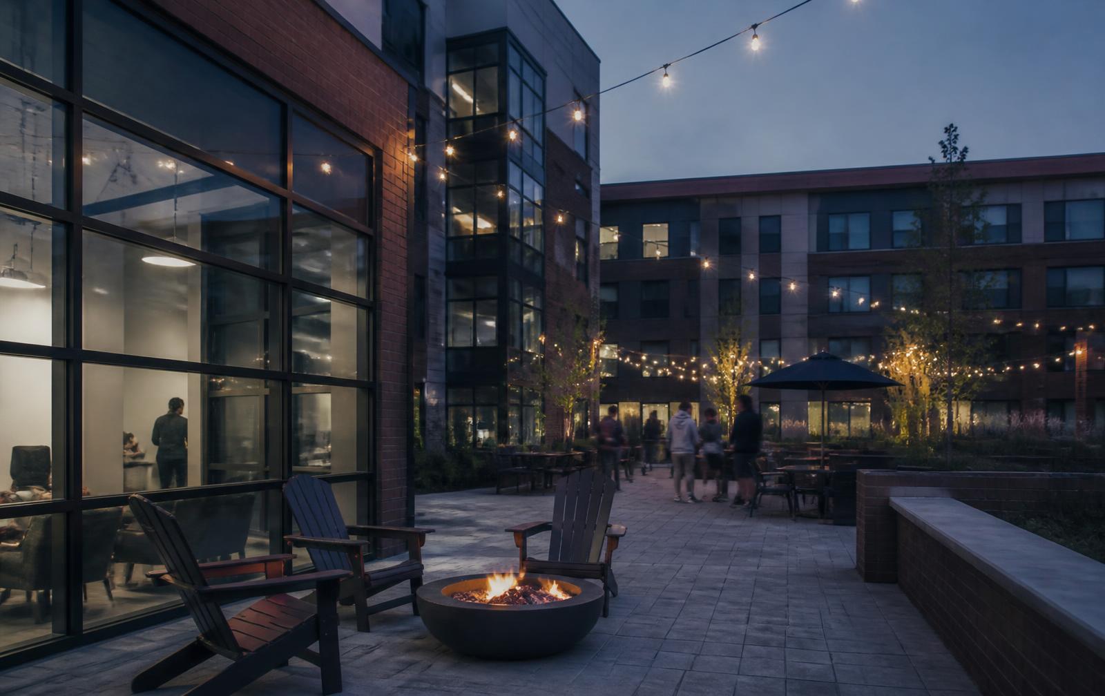 Student housing courtyard at dusk with string lights and residents